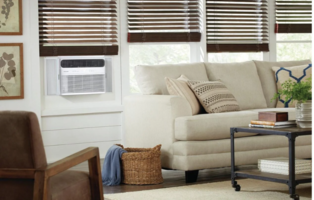 Frigidaire window air conditioner installed in a living room window beside a neutral sofa